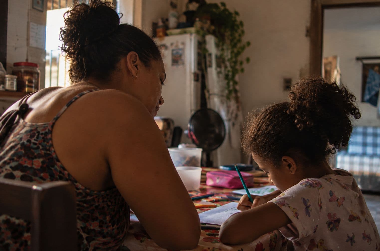 Mãe e filha desenhando juntas à mesa de casa